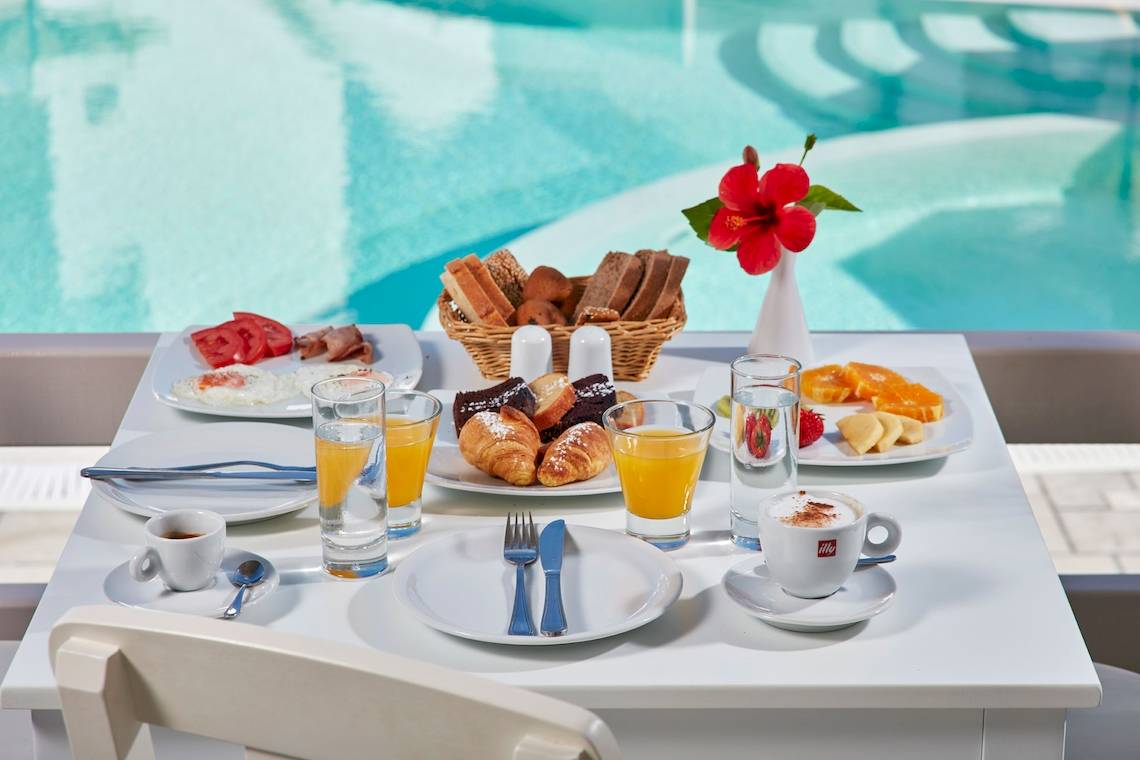 Frühstück am Pool im Aegean Plaza Hotel mit verschiedenen Speisen und Getränken.