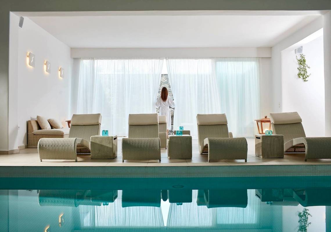 Lounge-Bereich am Pool im Aegean Plaza Hotel mit weißen Möbeln und großen Fenstern.