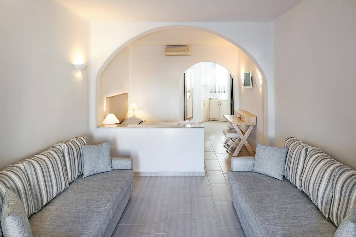 Wohnbereich des Aegean Plaza Hotels mit zwei Sofas, Tisch und Fernseher.