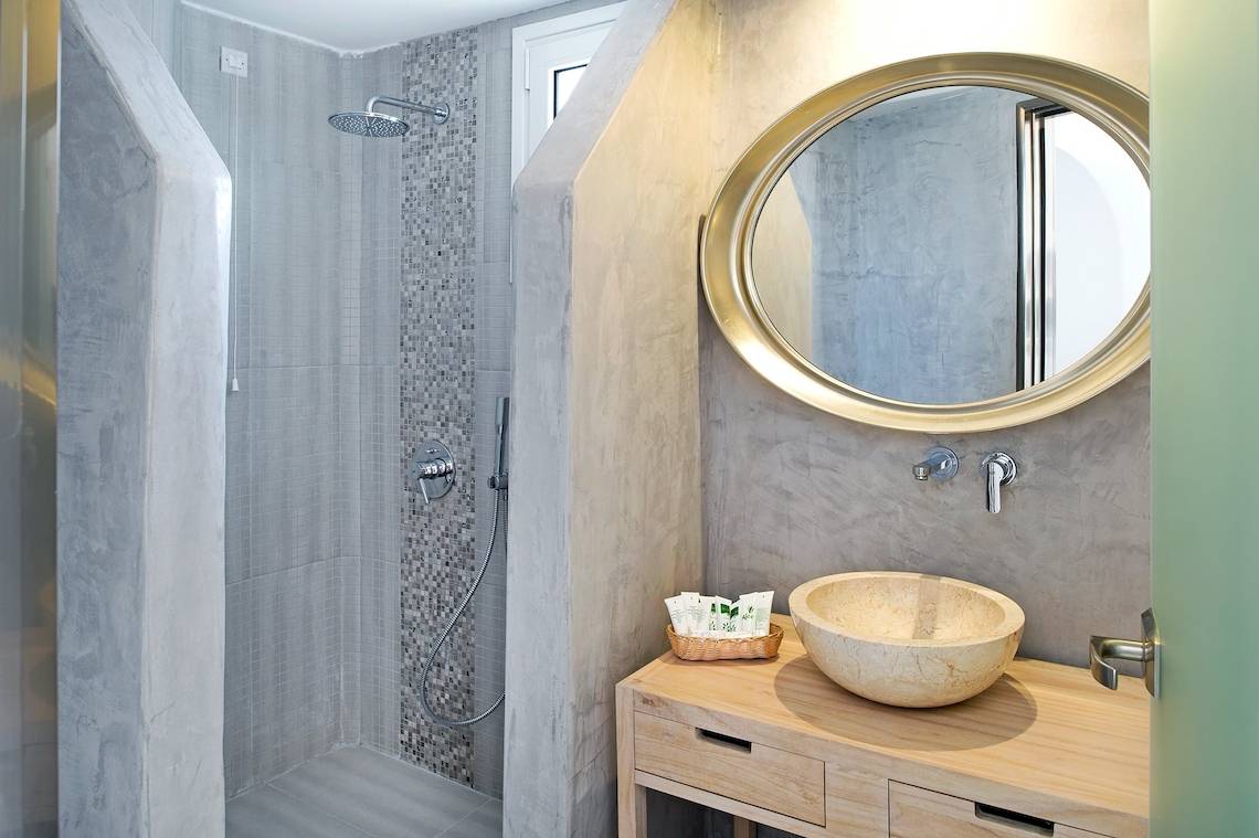 Badezimmer im Aegean Plaza Hotel mit Regendusche und ovalem Spiegel.