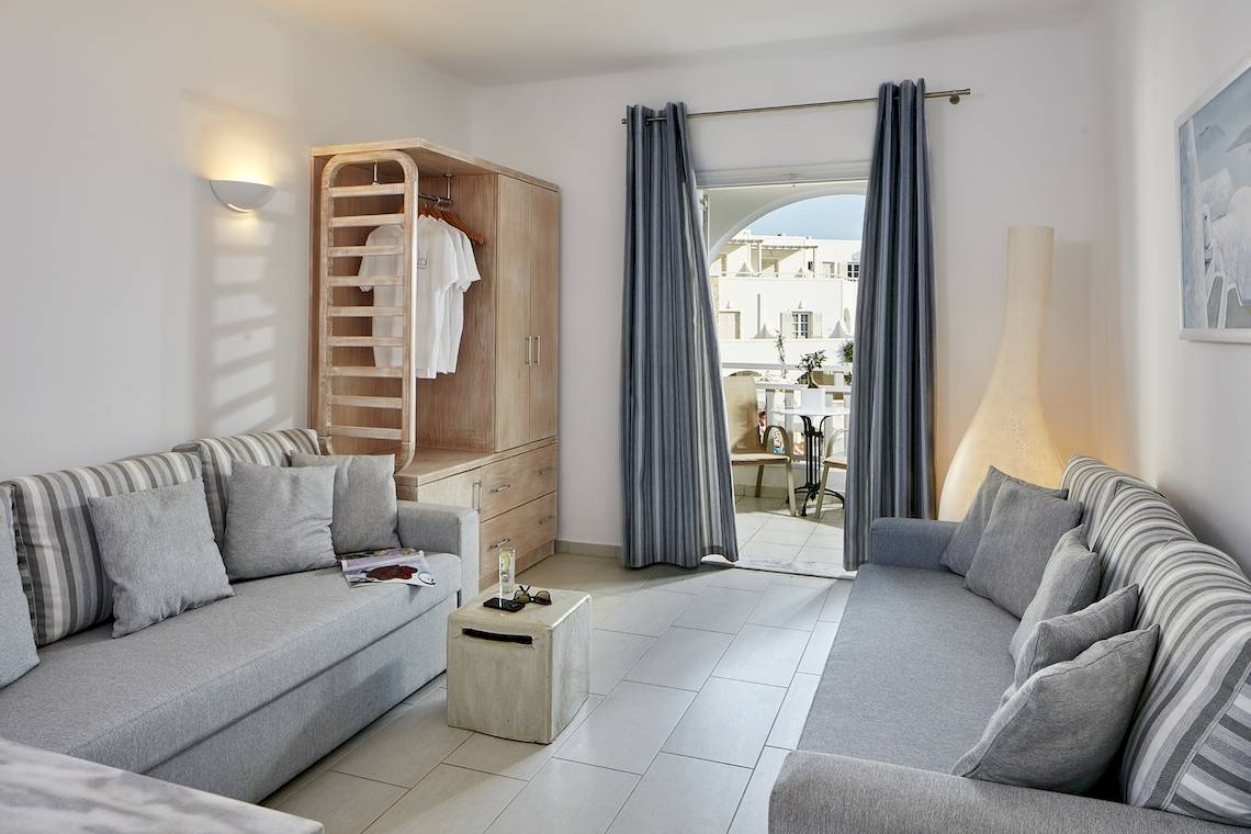 Wohnzimmer im Aegean Plaza Hotel mit zwei Sofas, einem Tisch, einem Kleiderschrank und einem Balkon.