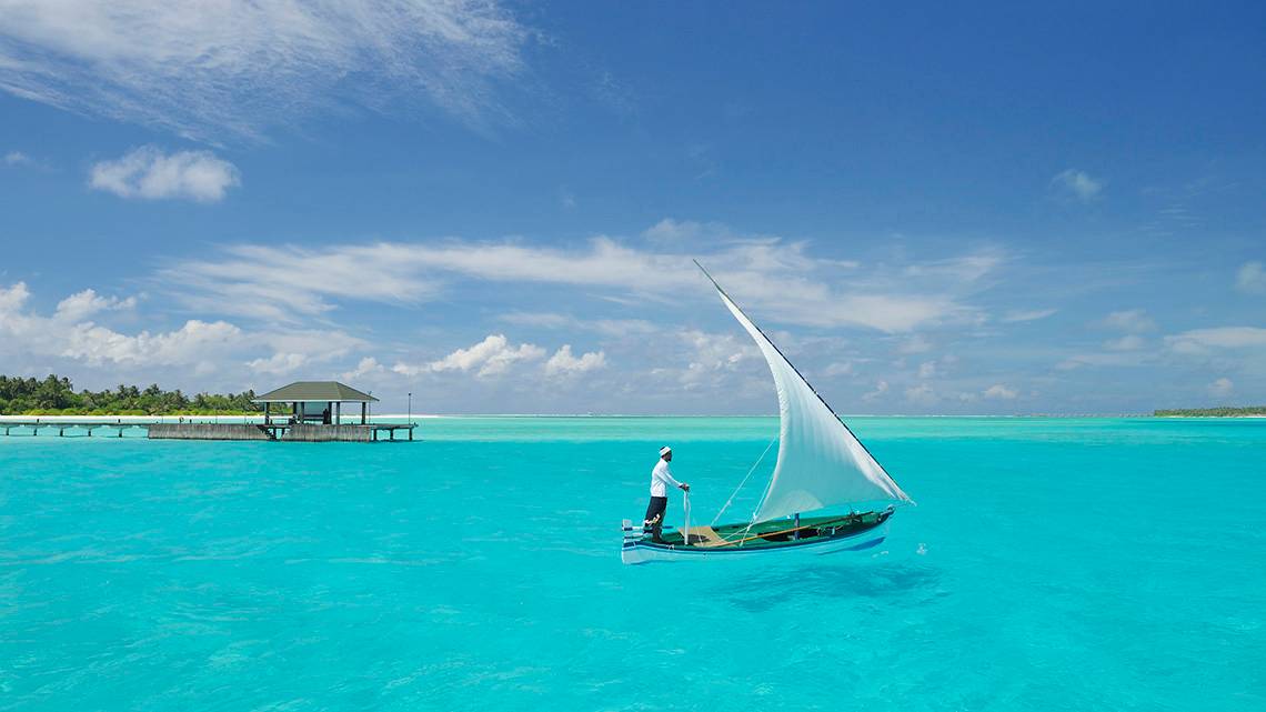 Mann auf einem Segelboot im kristallklaren Wasser des Holiday Island Resort & Spa