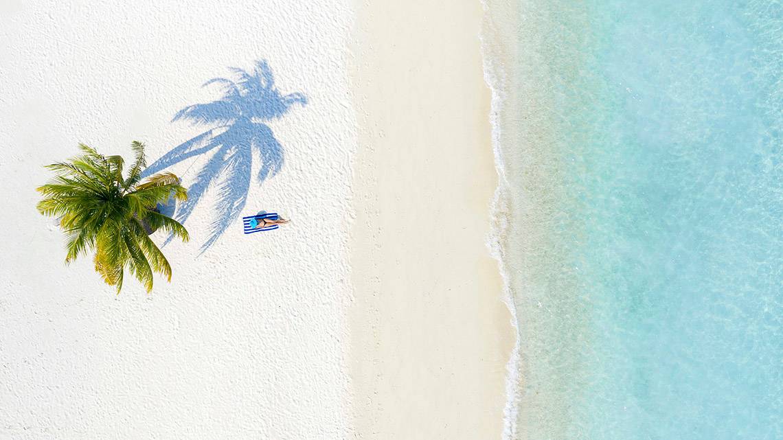 Strand mit Palme und Sonnenbank, Schatten auf dem Sand