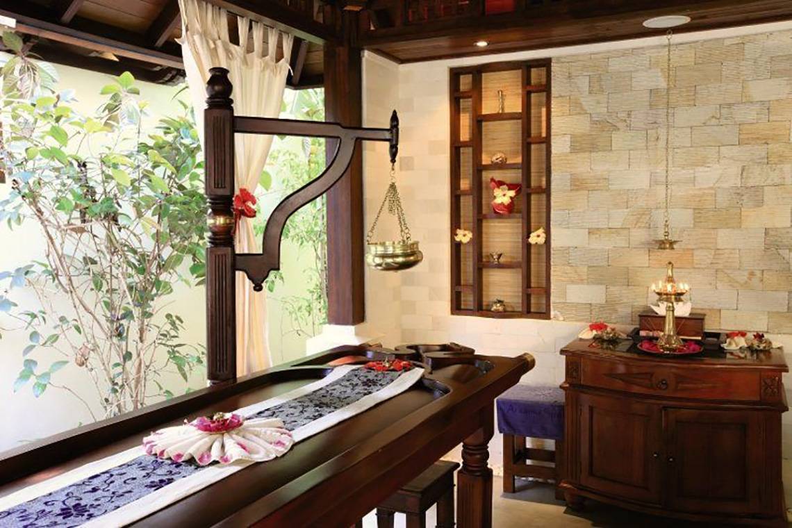 Massage-Behandlungsraum im Holiday Island Resort & Spa mit einem Tisch, einer Lampe und einer Wand mit Regalen.