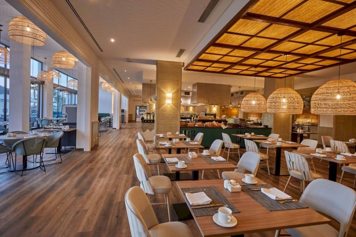 Innenansicht des Restaurants im Secrets Lanzarote Resort & Spa mit hölzernem Boden und modernen Möbeln.