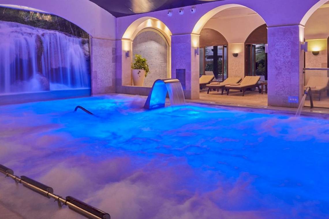 Poolbereich im Secrets Lanzarote Resort & Spa mit Wasserfall und Loungestühlen