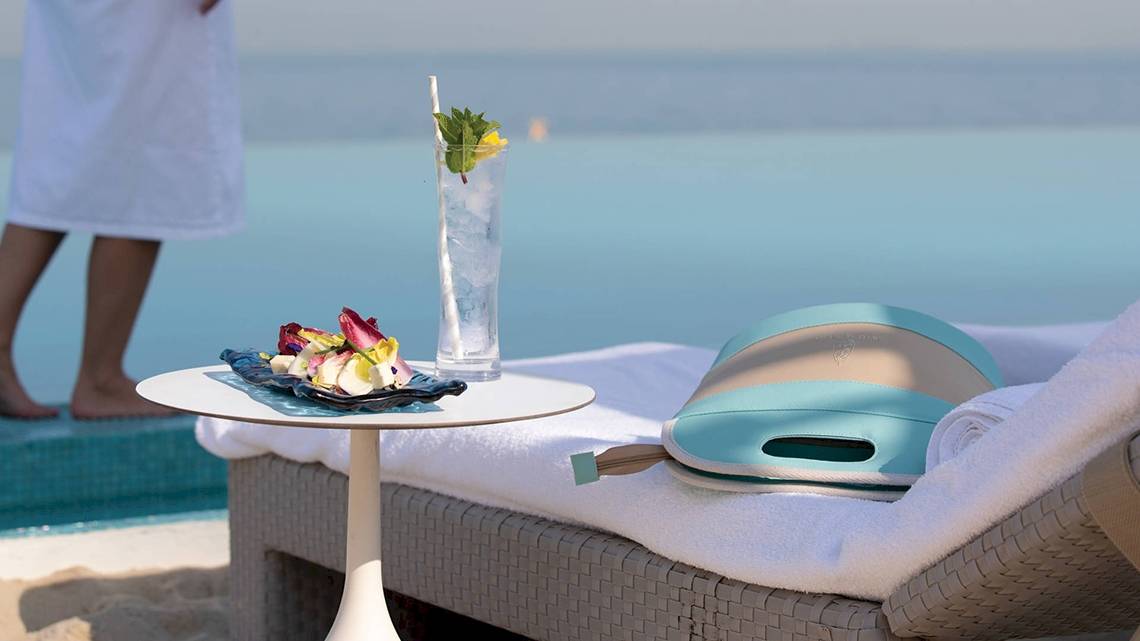 Person am Strand neben einem Tisch mit einem Getränk und einem Tablett mit Essen, Blick auf das Meer, Burj Al Arab Jumeirah