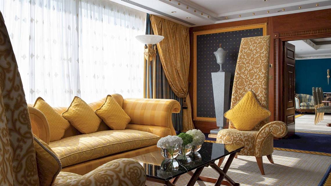 Wohnzimmer im Burj Al Arab Jumeirah mit gelben Möbeln und einer Glastisch.