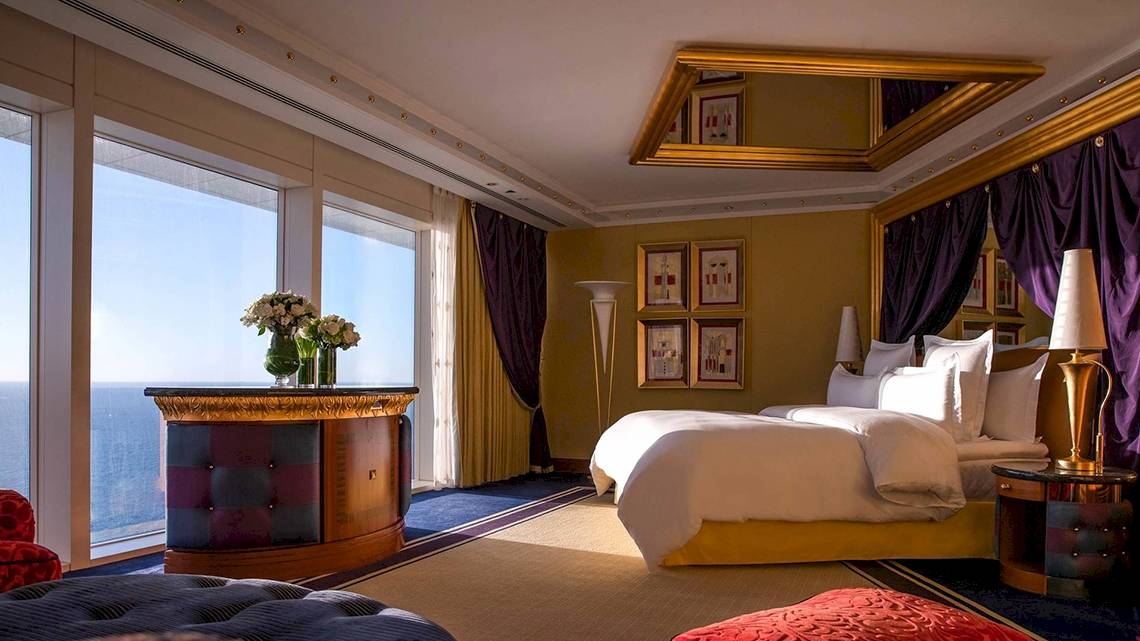 Schlafzimmer im Burj Al Arab Jumeirah mit Blick auf das Meer, einem großen Bett, Dekor und Blumen.