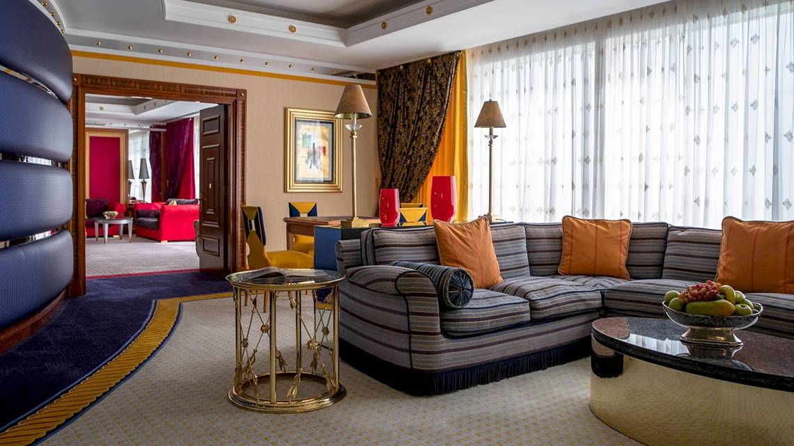 Wohnzimmer im Burj Al Arab Jumeirah Hotel mit blauen und orangefarbenen Möbeln und einem großen Sofa.