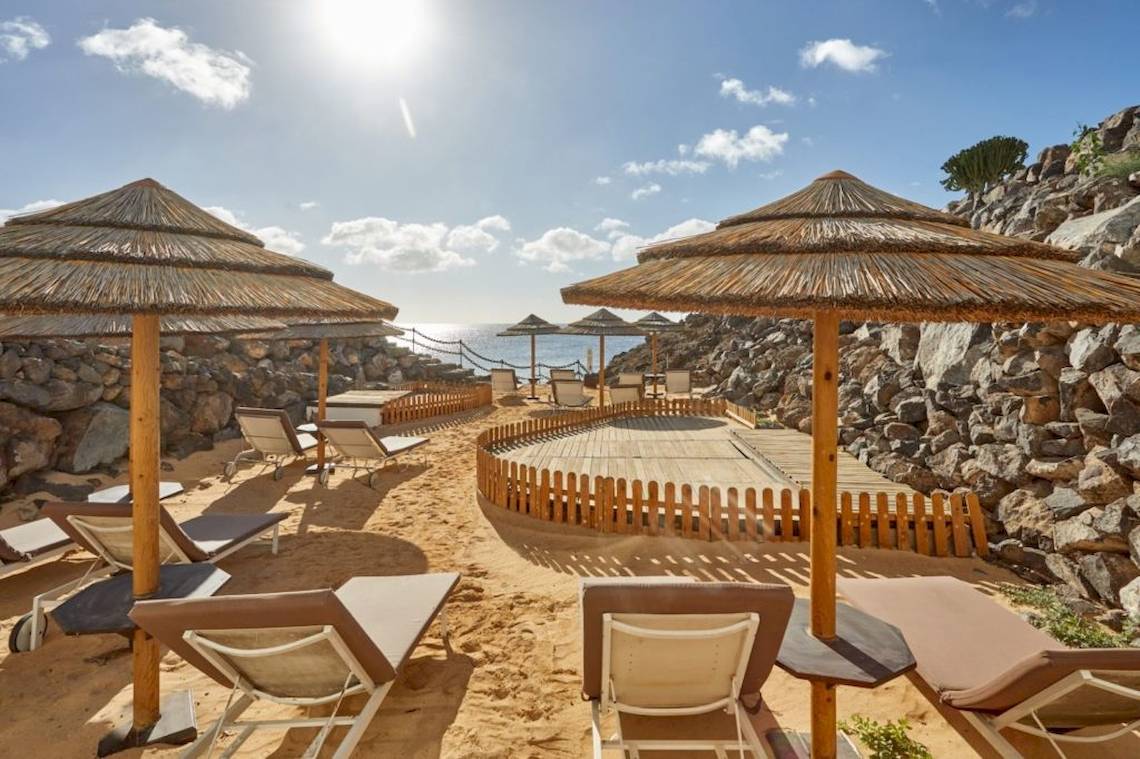 Strand-Lounge-Bereich des Secrets Lanzarote Resort & Spa mit Sonnenschirmen und Liegestühlen.