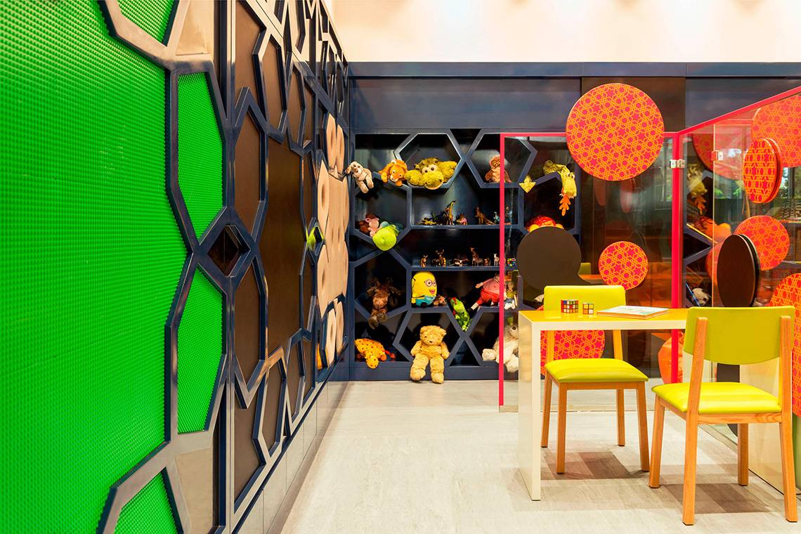 Kinderzimmer im Le Meridien Mina Seyahi Beach Resort mit grünen Wänden und gelben Stühlen.