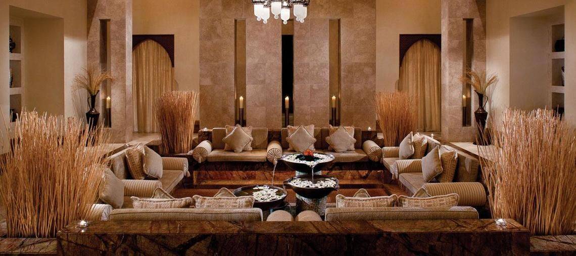 Innenbereich des Jumeirah Al Qasr Hotels mit vielen Sofas, Kissen, Vasen und Kerzen.