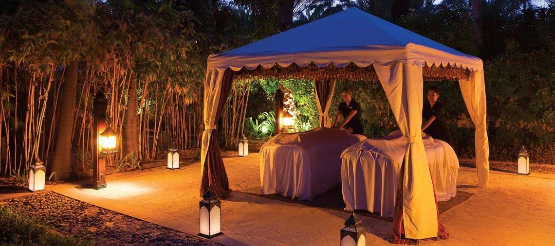 Zwei Mitarbeiter des Jumeirah Al Qasr Hotels bereiten ein Massagezelt unter freiem Himmel vor.