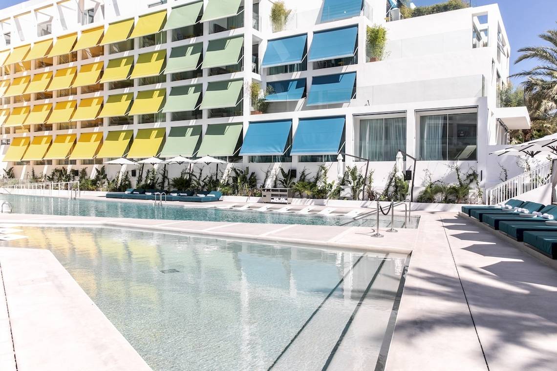 Außenansicht des W Ibiza Hotels mit Swimmingpool und Sonnenliegen.