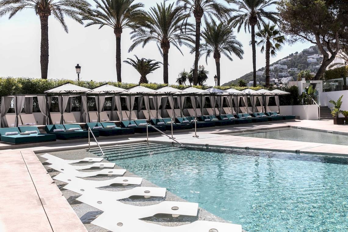 Pool-Lounge-Bereich des W Ibiza Hotels mit Sonnenliegen und weißen Sonnenschirmen.