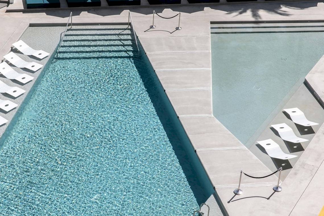 Luftaufnahme des Swimmingpools im W Ibiza Hotel mit weißen Sonnenliegen.