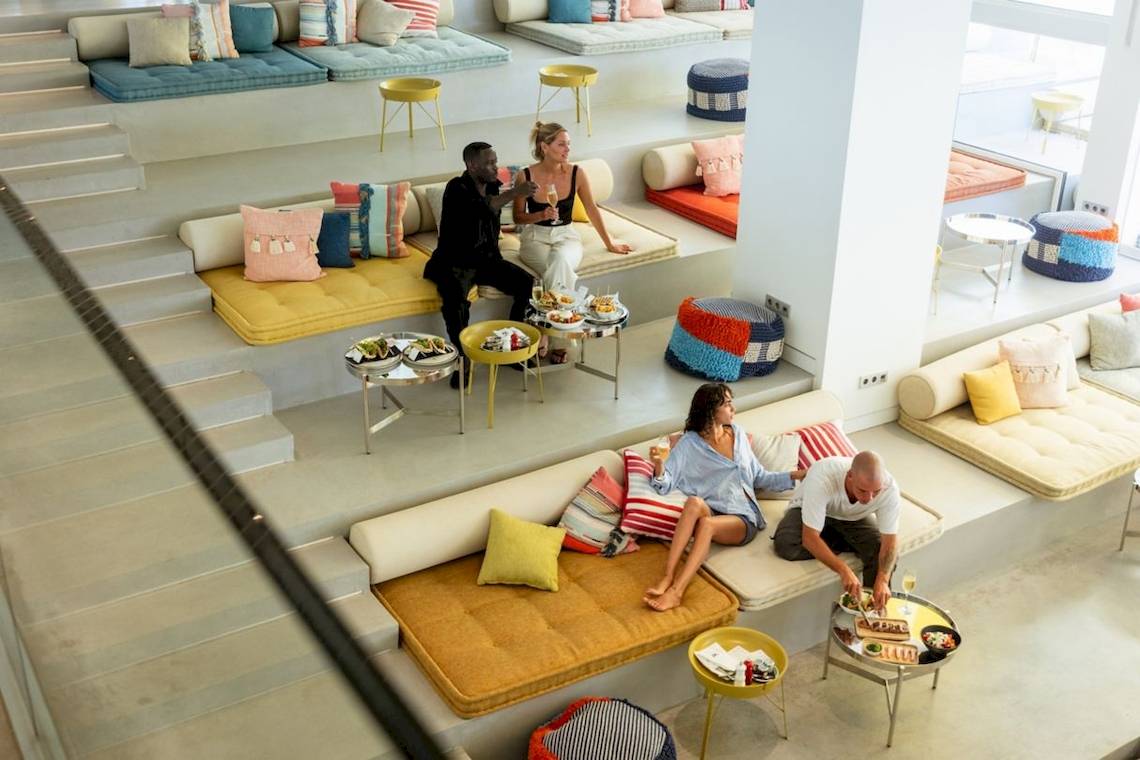 Loungebereich im W Ibiza Hotel mit mehreren Paaren, die auf Sofas sitzen und essen.