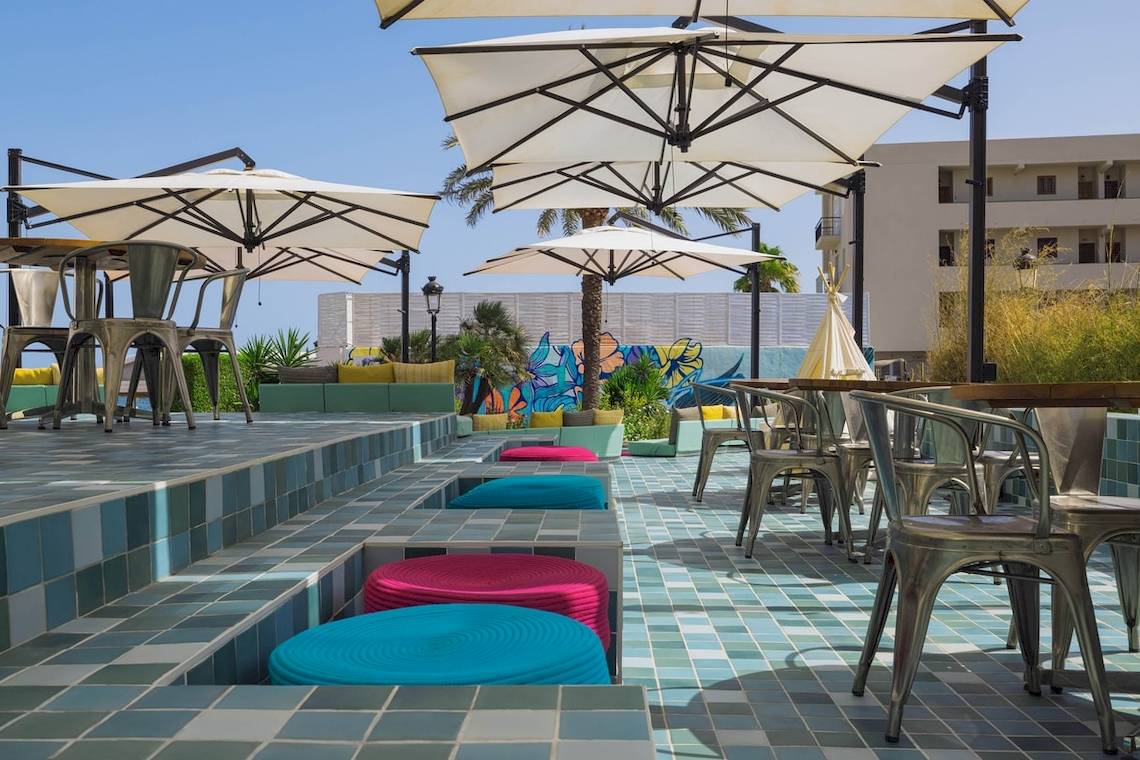 Terrasse im W Ibiza mit Sitzen, Tischen und Sonnenschirmen