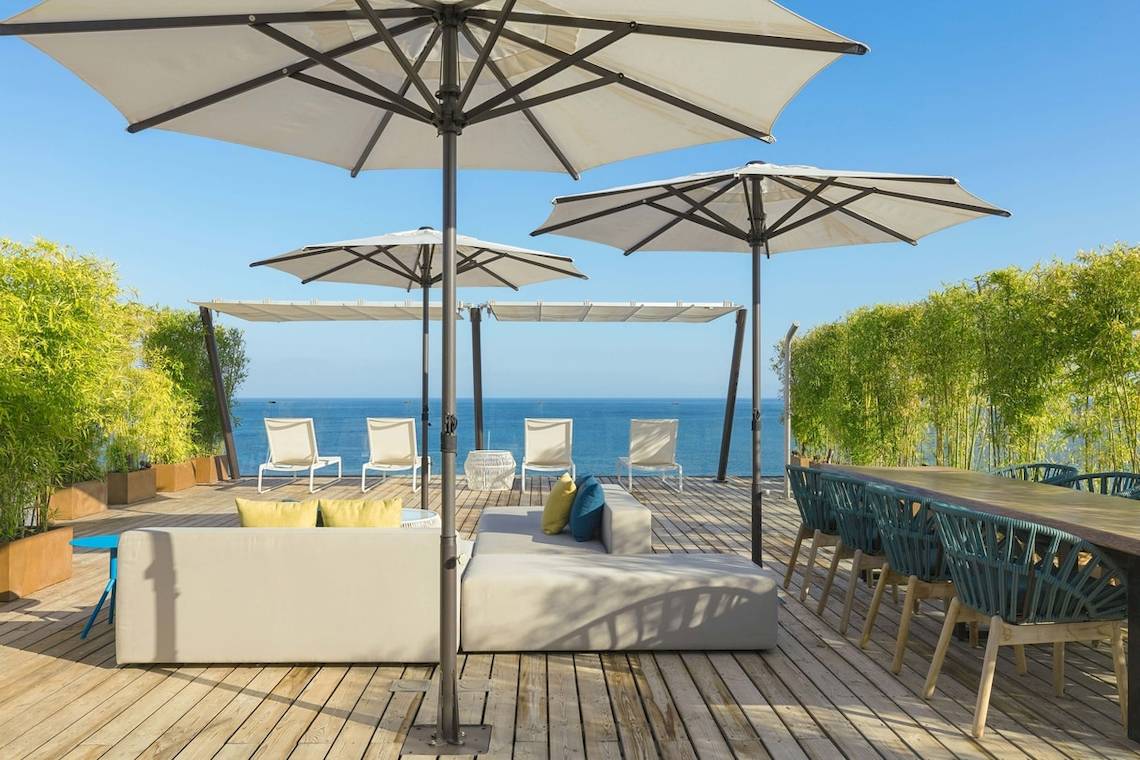 W Ibiza Hotel Terrasse mit Sofa und Sonnenschirmen am Meer