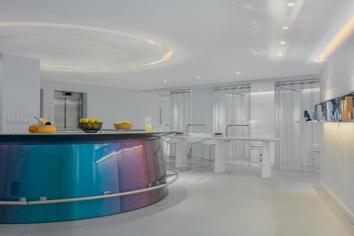 W Ibiza Hotel Innenraum mit Bar, blauer Theke, weißen Stühlen und Tisch.
