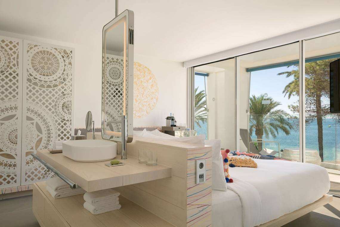 Badezimmer im W Ibiza Hotel mit Meerblick, großem Spiegel und heller Einrichtung.
