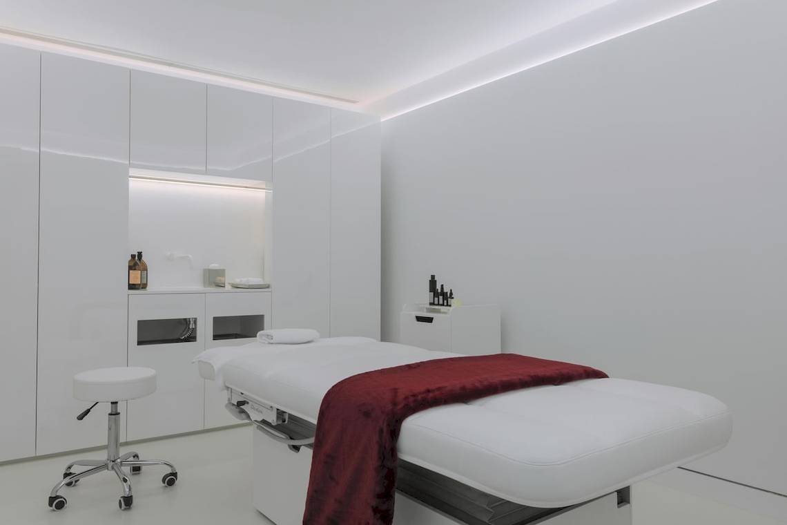 Behandlungsraum im W Ibiza Hotel mit weißem Behandlungstisch, rotem Tuch und weißem Stuhl