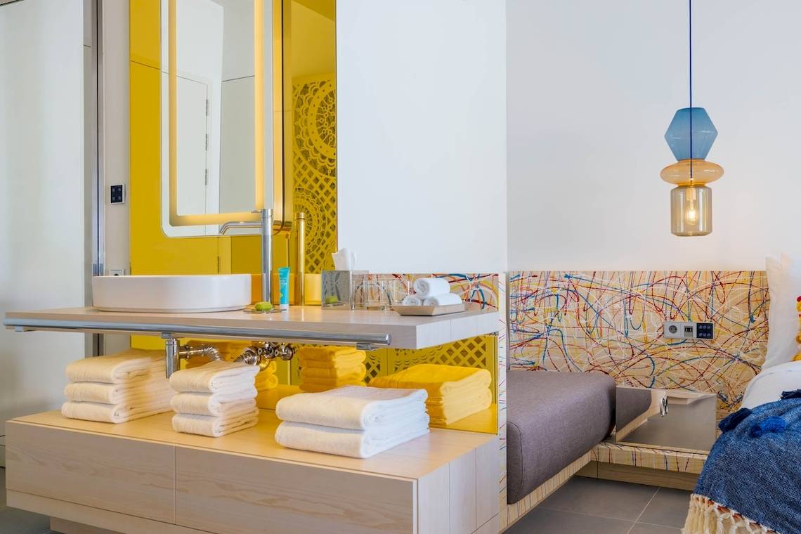 Badezimmer im W Ibiza Hotel mit Dusche, WC und farbenfroher Wandgestaltung.