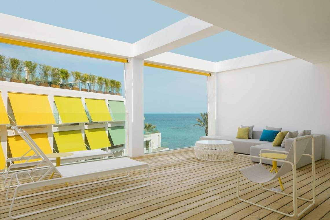 Außenterrasse des W Ibiza Hotels mit Blick auf das Meer und gelben Rollos