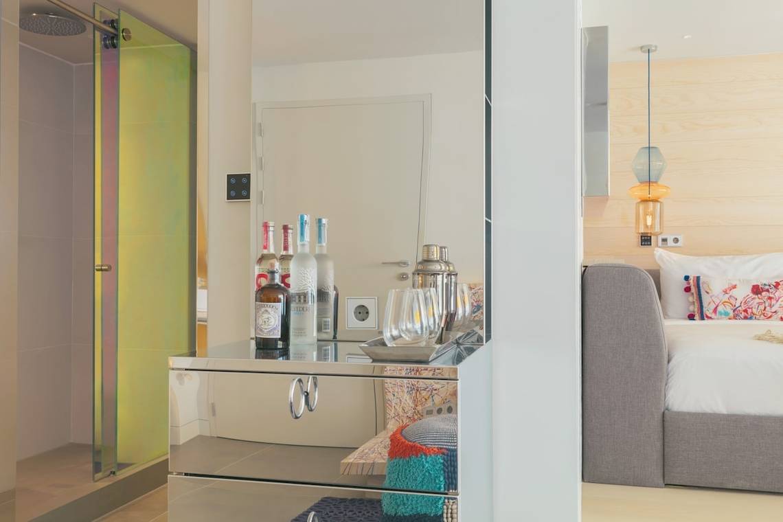 W Ibiza Hotelzimmer mit Spiegelschrank, Flaschen und Bett im Hintergrund