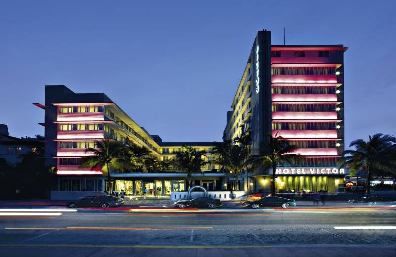 Das Hotel Victor South Beach ist in der Nacht beleuchtet und zeigt seine leuchtenden rosafarbenen Fassaden.
