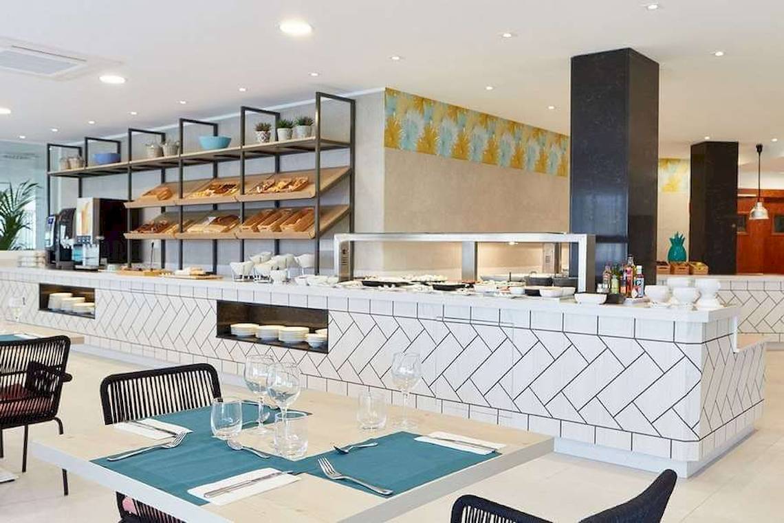 Frühstücksbereich im Universal Aparthotel Elisa mit Tisch, Stühlen und Buffet.