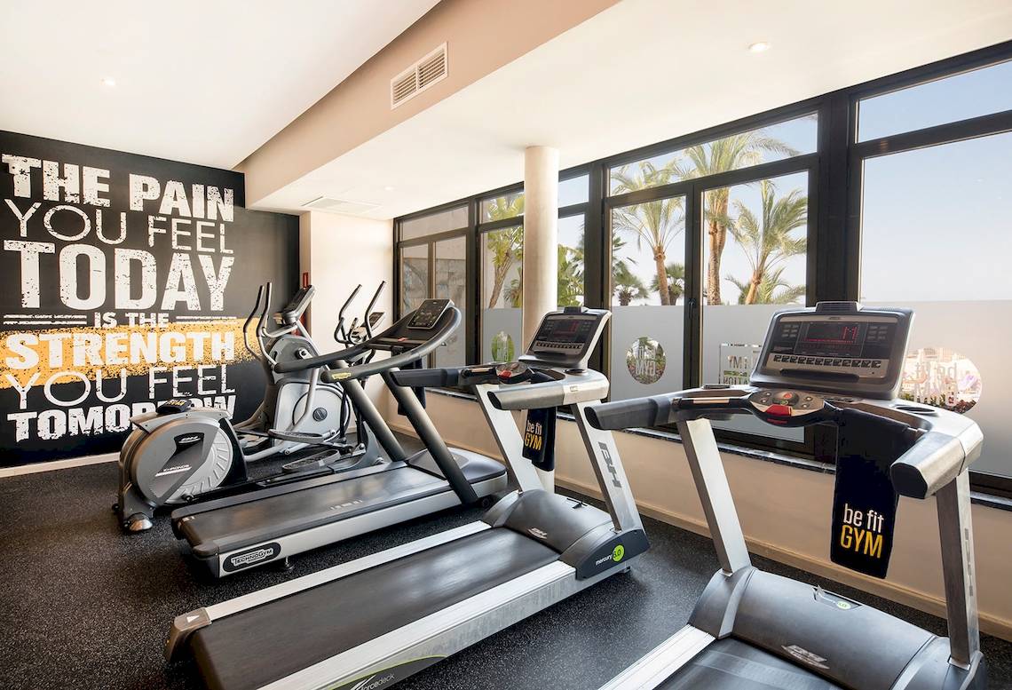 Fitnessstudio im Be Live Adults Only Marivent Hotel mit drei Laufbändern und einer Wand mit Trainingsmotto.