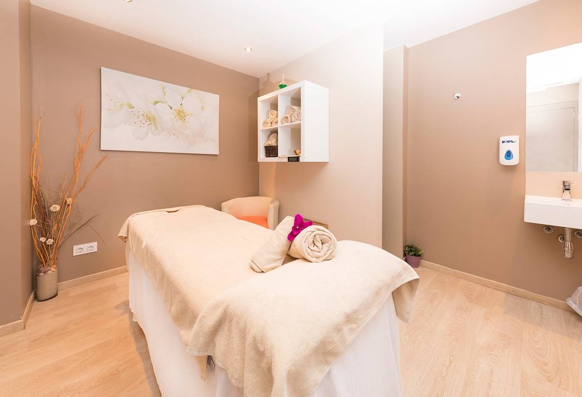 Massageraum im Be Live Adults Only Marivent Hotel mit Behandlungsliege, Stühlen und Dekoration.