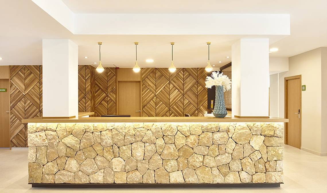 Empfangsbereich des Castell Royal Hotels mit Steinwand und Holzmustern