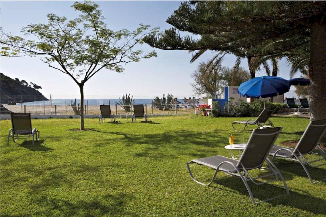 Gartenbereich des Castell Royal Hotels mit Sonnenliegen und Sonnenschirmen in der Nähe des Strandes