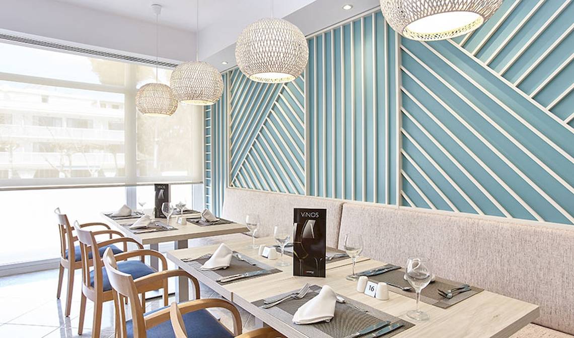 Innenansicht des Restaurants im Castell Royal Hotel mit blauen Wänden und Holztischen.