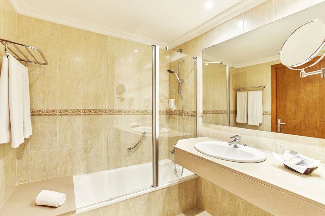 Badezimmer im Castell Royal Hotel mit Dusche, Badewanne und Spiegel.