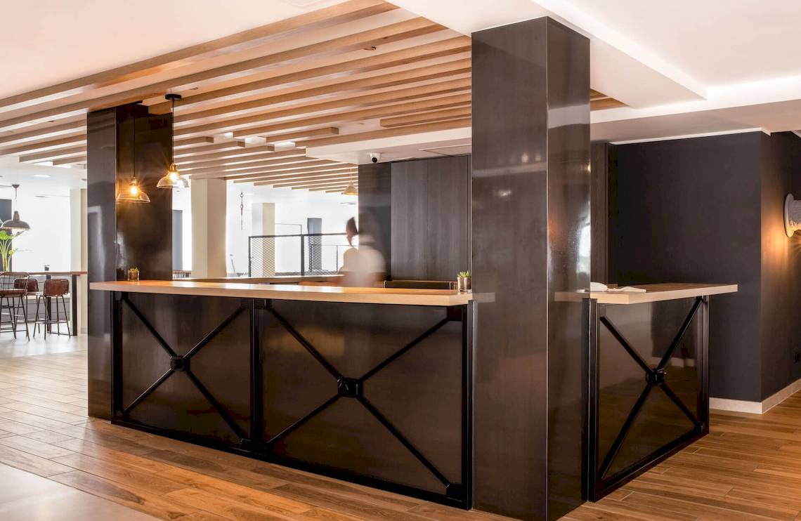 Rezeption im Florida Magaluf Hotel mit Holzboden und schwarzen Metallelementen.
