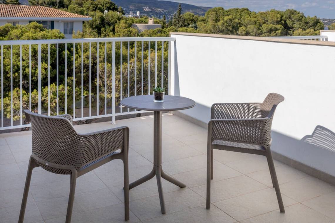 Ein Balkon des Florida Magaluf Hotels mit Tisch, Stühlen und Ausblick auf eine bewaldete Landschaft.