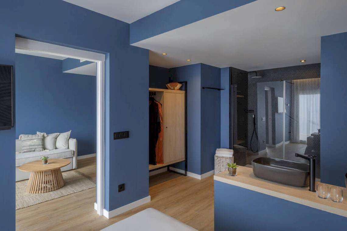Inneneinrichtung eines Zimmers im Florida Magaluf Hotel mit blauen Wänden, Holzboden und modernem Badezimmer.