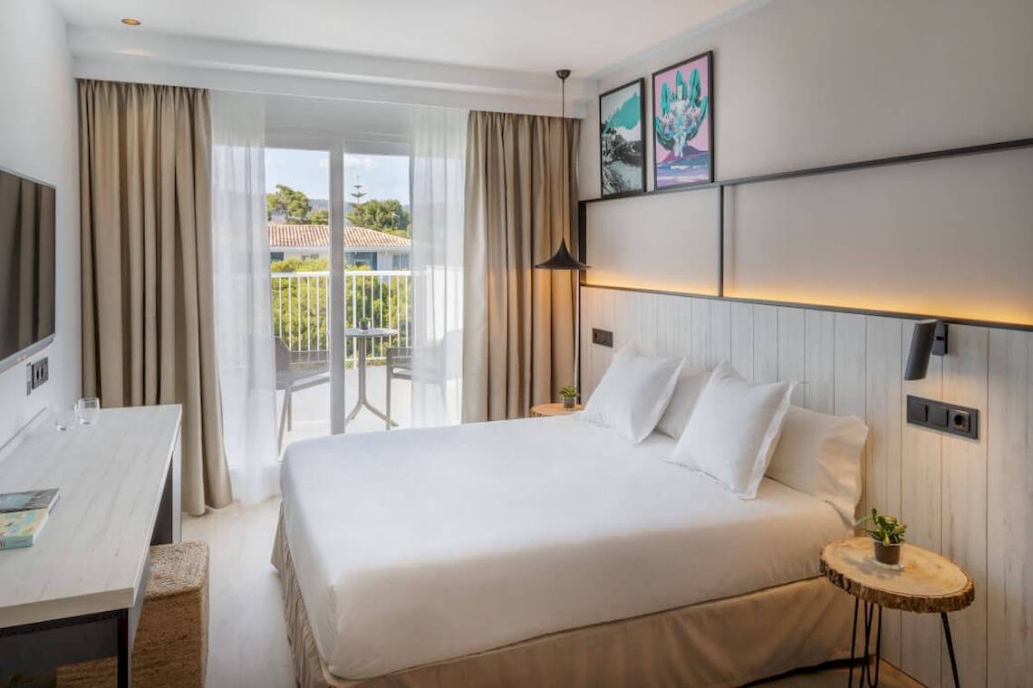 Ein modernes Hotelzimmer im Florida Magaluf mit einem Doppelbett, einem Schreibtisch und einem Balkon.