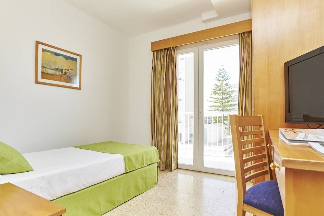 Ein Hotelzimmer mit einem Bett, einem Schreibtisch, einem Stuhl und einem Balkon.