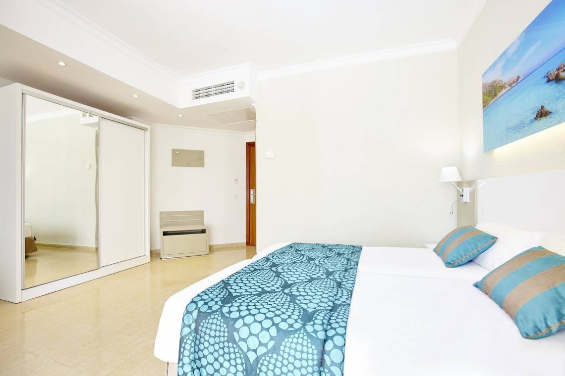 Schlafzimmer im Lido Park Hotel mit Doppelbett, Deckenlampe, Spiegel und Gemälde.