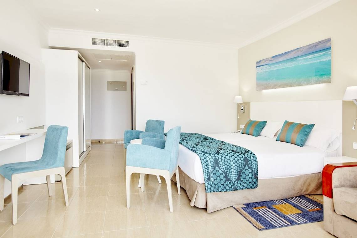 Innenansicht eines modernen Hotelzimmers im Lido Park Hotel mit einem großen Bett, Schreibtisch und Fernseher.