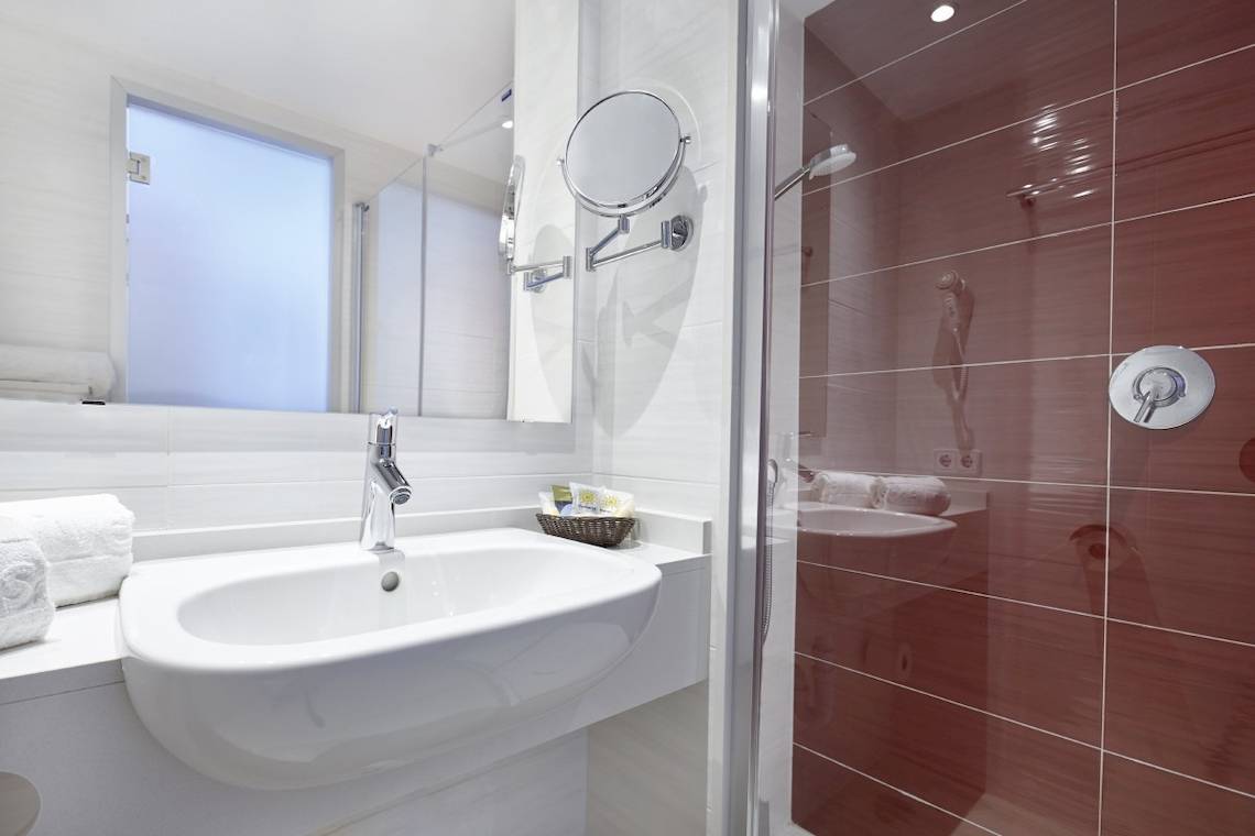 Badezimmer des Perla Hotels mit einem Spiegel und einer roten gefliesten Dusche.