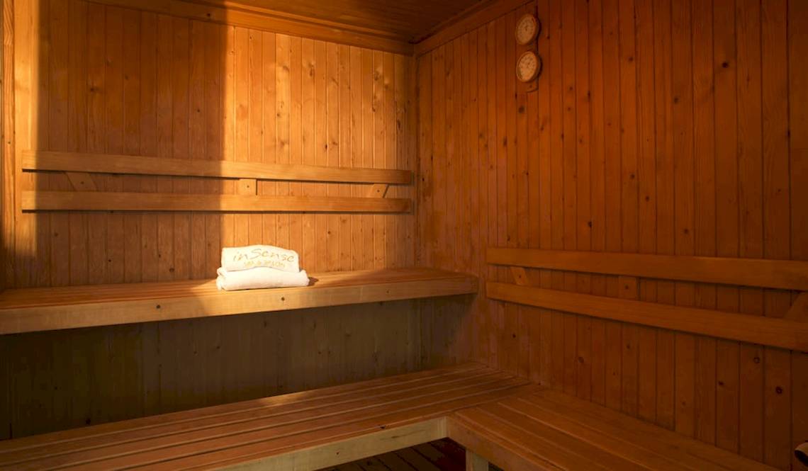 Sauna im Coral Costa Caribe Beach Resort mit leeren Holzbänken und Handtüchern.