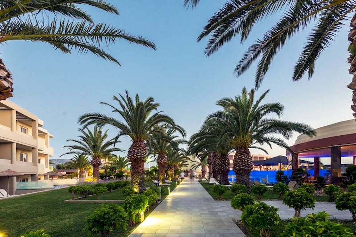 Außenbereich des Sandy Beach Hotels in Kos mit Palmen und Gebäuden