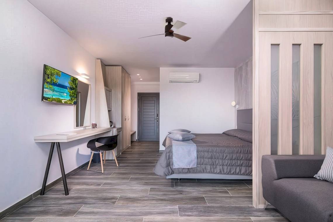 Innenansicht eines Zimmers im Sandy Beach Hotel auf Kos mit Bett, Schreibtisch, Fernseher und Klimaanlage.