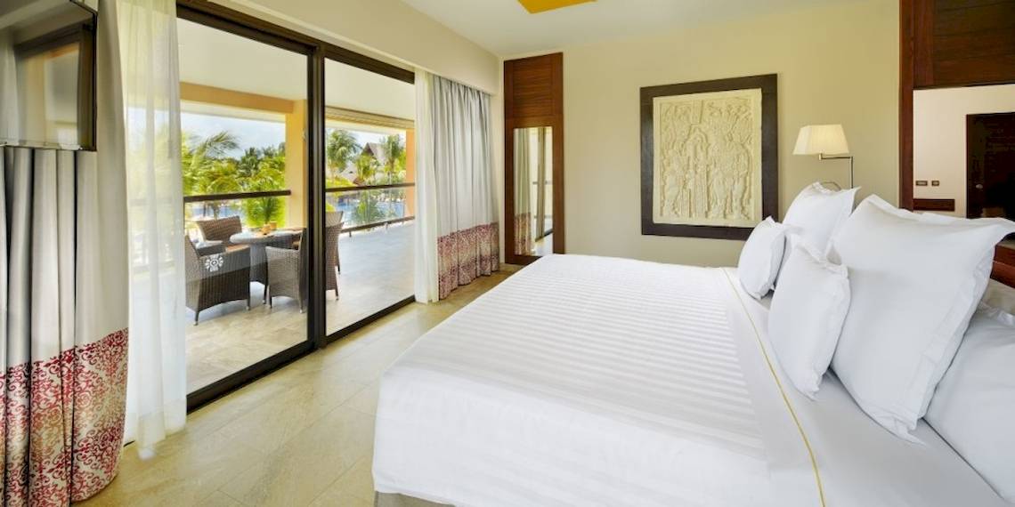 Schlafzimmer des Barcelo Maya Beach Hotels mit Terrasse und Ausblick auf den Pool.